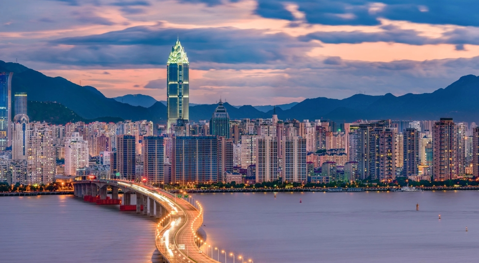 Une vue aerienne panoramique de la silhouette de la ville de Wenzhou au crepuscule, mettant en scene un long pont illumine qui s etire au dessus de la riviere Oujiang vers le centre ville Une vue aerienne panoramique de la silhouette de la ville de Wenzhou au crepuscule, mettant en scene un long pont illumine qui s etire au dessus de la riviere Oujiang vers le centre ville